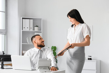 Fototapeta premium Young secretary showing documents to her boss in office
