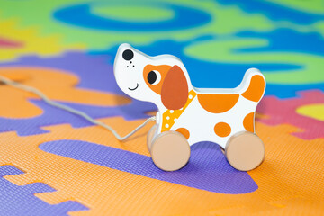 Wooden toy dog on a children play mat.