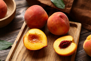 Cutting board with sweet ripe peaches on wooden background, closeup
