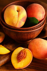 Bowl with sweet ripe peaches on wooden background, closeup