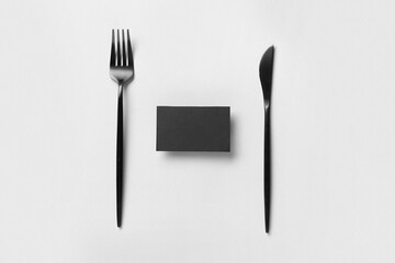 Black blank business card with cutlery on grey background