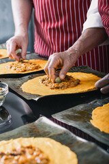 Hands placing olives on hallaca filling, traditional Venezuelan dish