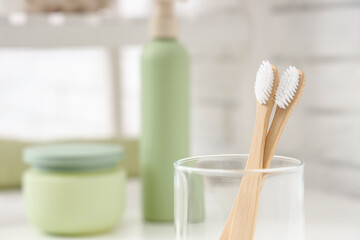 Glass cup with toothbrushes on table in bathroom, closeup