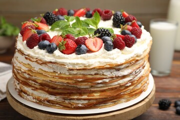 Delicious crepe cake with fresh berries on table, closeup