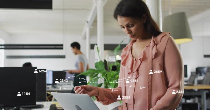 Monitoring overlaid metrics on laptop, mid-adult woman of color at desk in open office, copy space