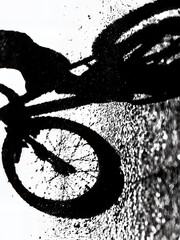 Fototapeta premium Abstract shadow of cyclist and bicycle on asphalt, high-contrast black and white