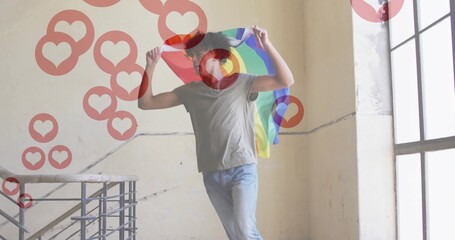 Fototapeta premium Man holding rainbow pride flag above head on staircase landing, with railing, floating heart icons