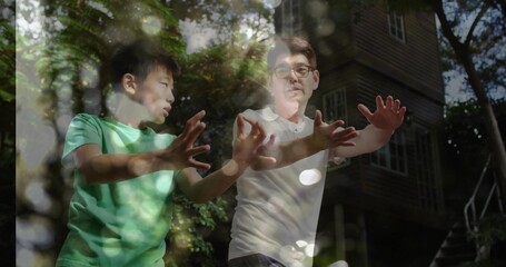 Practicing martial arts father and son extending arms outdoors in forest by cabin, dappled sunlight