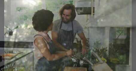 Cooking couple wearing striped aprons preparing meal in kitchen, chopping carrots, stirring pot