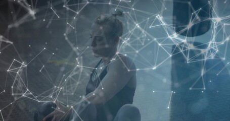 Resting female athlete wearing sportswear on gym mat, with kettlebell and digital overlay