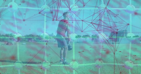Performing kettlebell squat mid adult male in workout clothes on grassy field, with yellow poles