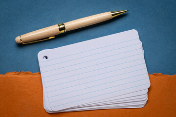 stack of blank index cards with a pen against textured bark paper