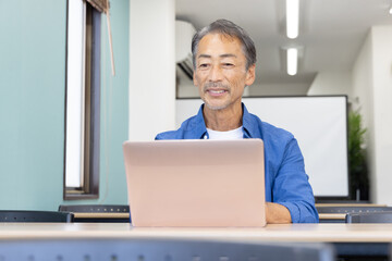 ノートパソコンを使うシニア男性