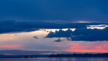 Post-sunset twilight illuminates the clouds in vibrant pinks and blues over the Reloncaví Estuary, with a pontoon in the still water.
