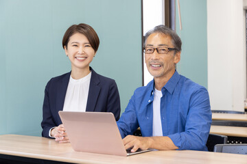 Fototapeta premium パソコン教室に通うシニアと教える講師