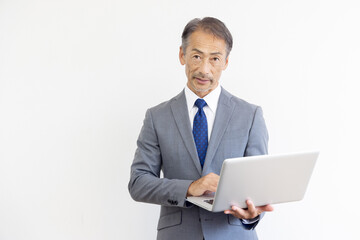 ノートパソコンを使うシニア男性