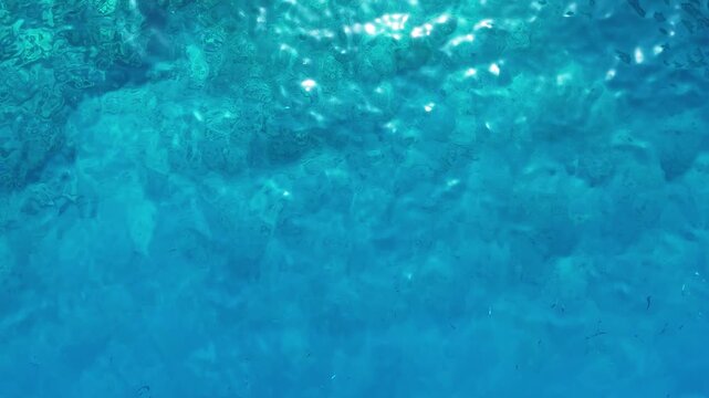 A simple and beautiful video of a calm blue water surface with sparkling light reflections creating a mesmerizing and abstract texture perfect for a relaxing background