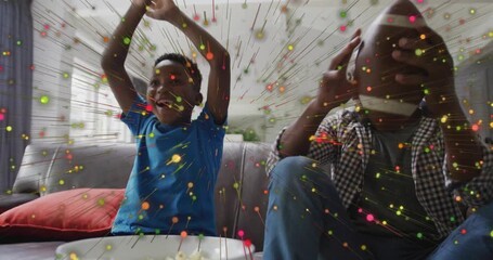 Father and son reacting to confetti and celebrating football win on couch, showcasing technology - Powered by Adobe