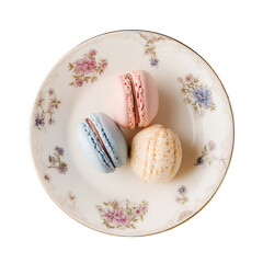 Three colorful macarons arranged on a vintage floral patterned ceramic plate, top-down view.
