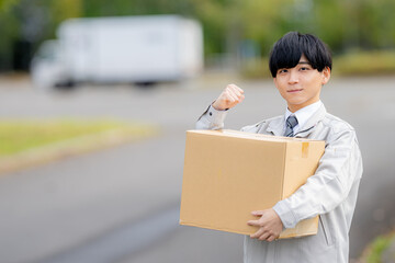 段ボールとガッツポーズする作業服男性