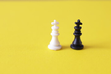 Una toma de cerca de varias piezas de un juego de ajedrez de color blanco y negro en una fondo amarillo