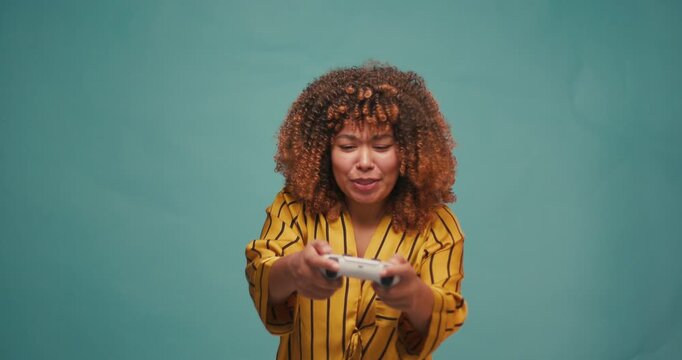 Hispanic Latin Woman Playing Game Online at Blue Backdrop. Gamer Female Controlling Joystick for Video Game. Leisure Game Cyberpunk Concept