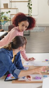 Collaborating diverse female coworkers reviewing wireframes at design studio, with sticky notes