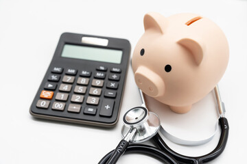 Calculator, Piggy bank and stethoscope on white background health medicine theme with copy space....
