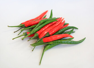 Red and green chili peppers against white background, preparation process of chilli for cooking.