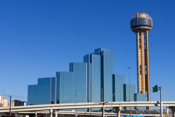 Panoramic view of Downtown Dallas skyline and modern Reunion tower landmark against blue sky.