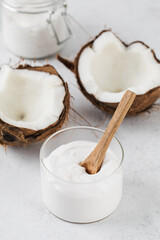 Fresh coconut yogurt in a glass jar with a wooden spoon and coconuts. Vegan yogurt, lactose-free.