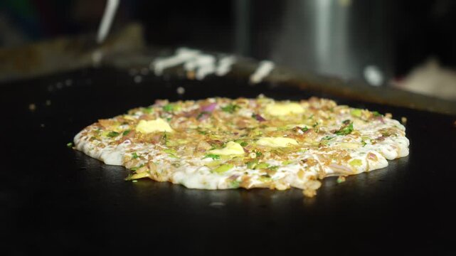  Onion dosa being cooked on a hot iron tawa. Popular South Indian street food breakfast..