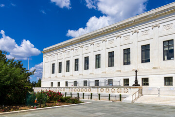 Obraz premium A white marble government building with lush green trees and plants in Washington DC USA