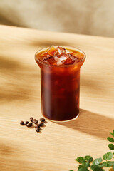 Refreshing Iced Black Coffee in Glass on Wooden Table, Iced coffee in a glass on a wooden table with coffee beans
