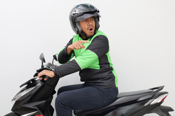 Angry asian online driver man shouting and pointing behind him while driving a motorcycle. Isolated...