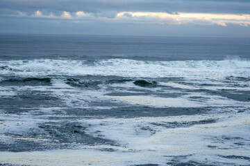 Seascape of the Pacific Ocean along the Oregon coast on an overcast cloudy day with crashing waves  and foamy seas