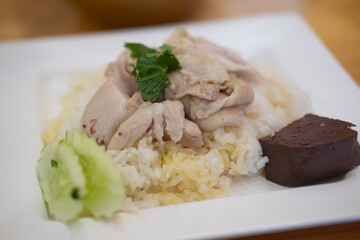 Steamed rice topped with chicken in a white plate