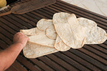 Hand preparing traditional flatbreads on a griddle