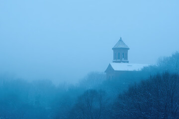 silhouette of bell tower emerges from dense fog of winter morning captured beautifully