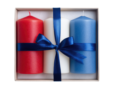 Three pillar candles in red, white, and blue, nestled in a gift box, tied with a blue ribbon