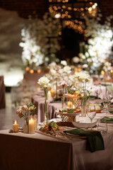 Wedding banquet table decorated with candles, flowers and food in elegant restaurant interior with brick wall. Concept of celebration, romance, reception, event decoration.