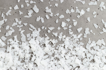 Close-up of magnesium flakes on gray concrete background, salt crystalline texture. Natural White sea salt as wellness or spa products for bath or relaxation, self-care or sustainable living