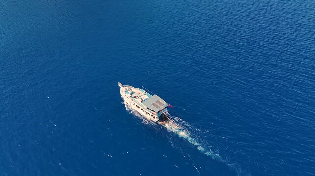 An aerial drone video of a classic wooden gulet style tour boat cruising on the beautiful deep blue sea a traditional and luxurious way to travel and explore the coast