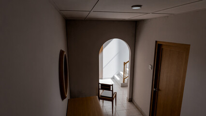 Minimalist 3D render of a quiet interior corner with chair, wooden furniture, and natural light through an archway. Perfect for concepts of solitude, design, or architectural art.