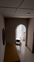 Minimalist 3D render of a quiet interior corner with chair, wooden furniture, and natural light through an archway. Perfect for concepts of solitude, design, or architectural art.