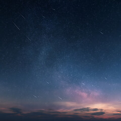 Fototapeta premium Distant shooting stars streak across a vast, starry night sky with a hint of twilight glow.