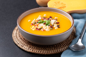 Butternut squash pumpkin soup with granola in a bowl on black background, Homemade food in autumn season