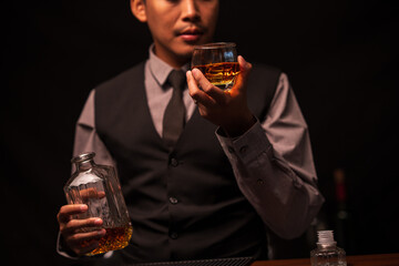 Business man bartender pours whiskey into a glass, sitting sadly in a restaurant	