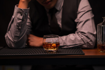 Business man bartender pours whiskey into a glass, sitting sadly in a restaurant	