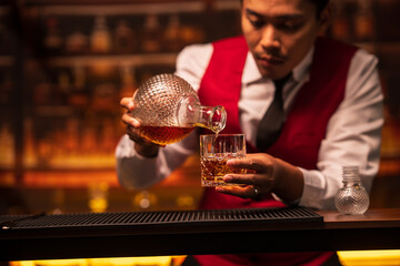 Bartender is pouring whiskey into a glass in a restaurant	